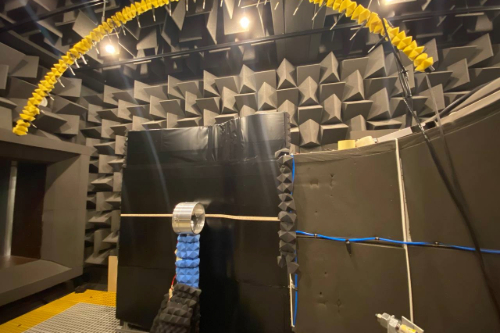 BLI ducted fan test rig inside the anechoic chamber at the University of Bristol, featuring a ducted fan mounted on the curved S-plate and an overhead microphone array for aeroacoustic measurements.